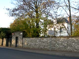 Une maison de caractère, dans un parc entouré de murs en pierre.